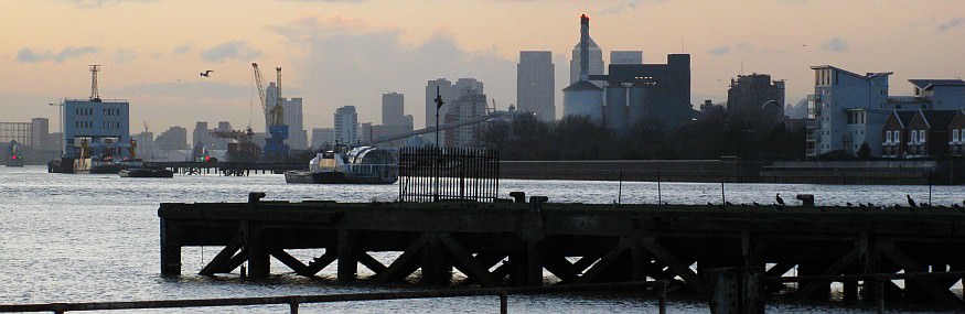 Looking from the former canal entrance, across the coal pier, towards the Woolwich free ferry, the Thames Barrier, Canary Wharf and Central London